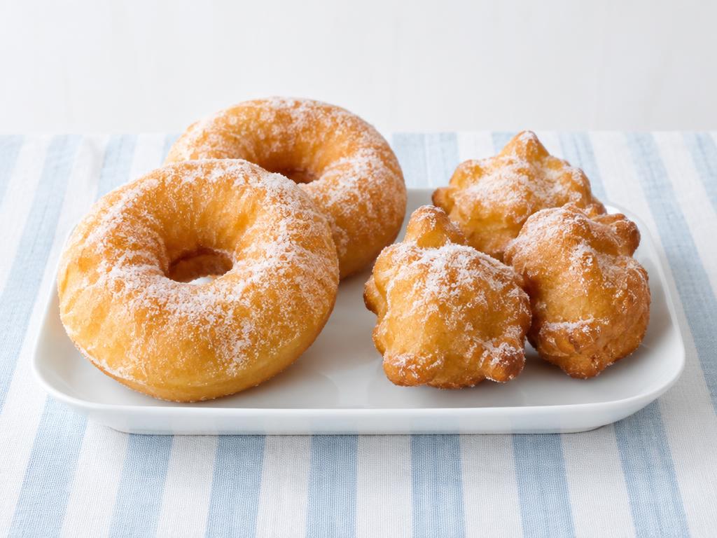 Ciambelle ad anello e frittelle dorate su un vassoio bianco